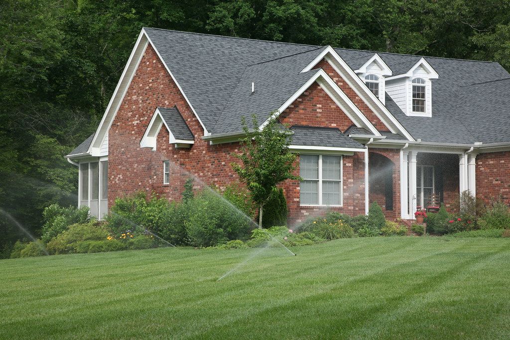 An in-ground sprinkler system running across a healthy front lawn