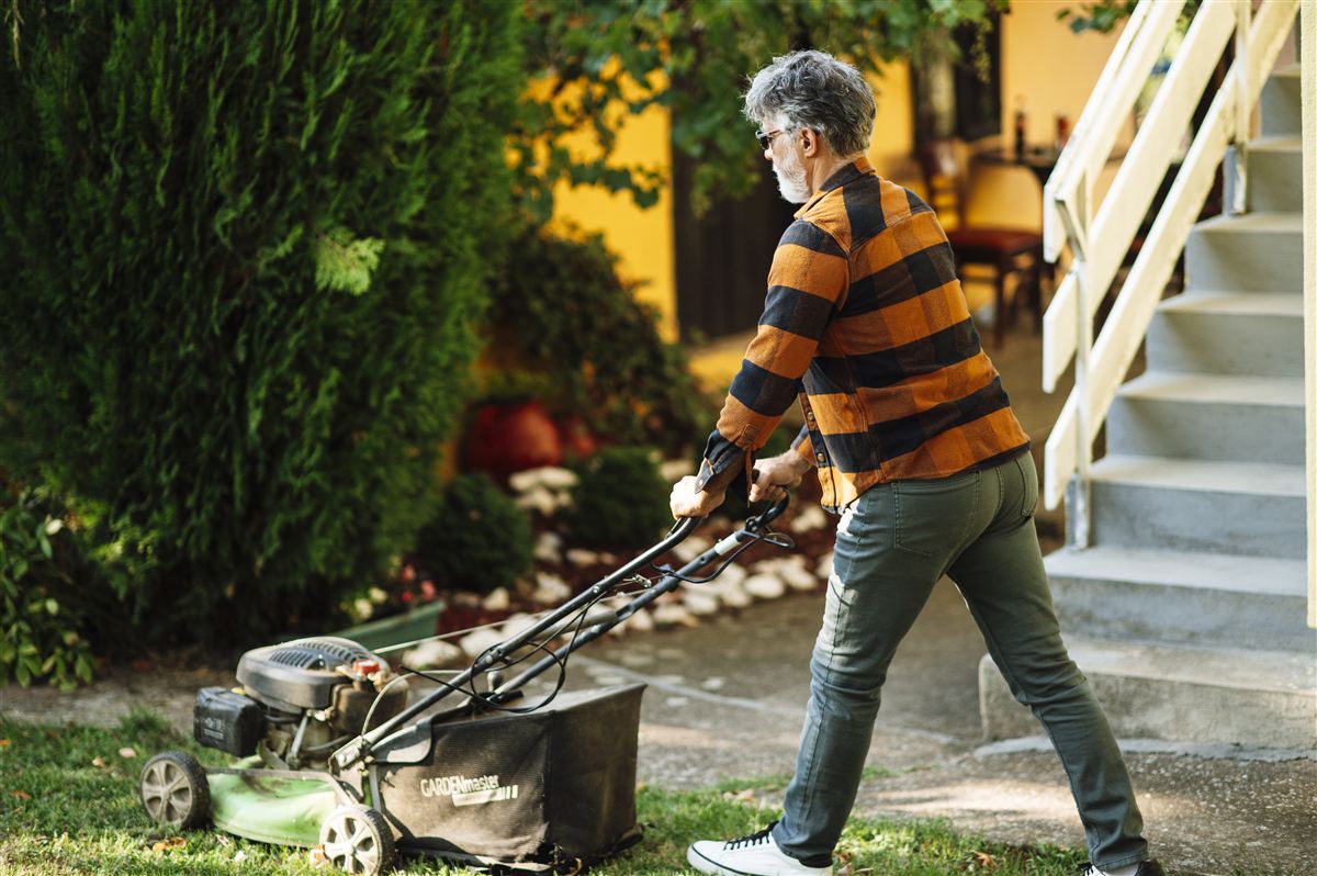 A gardener pushing a mower across a residential lawn