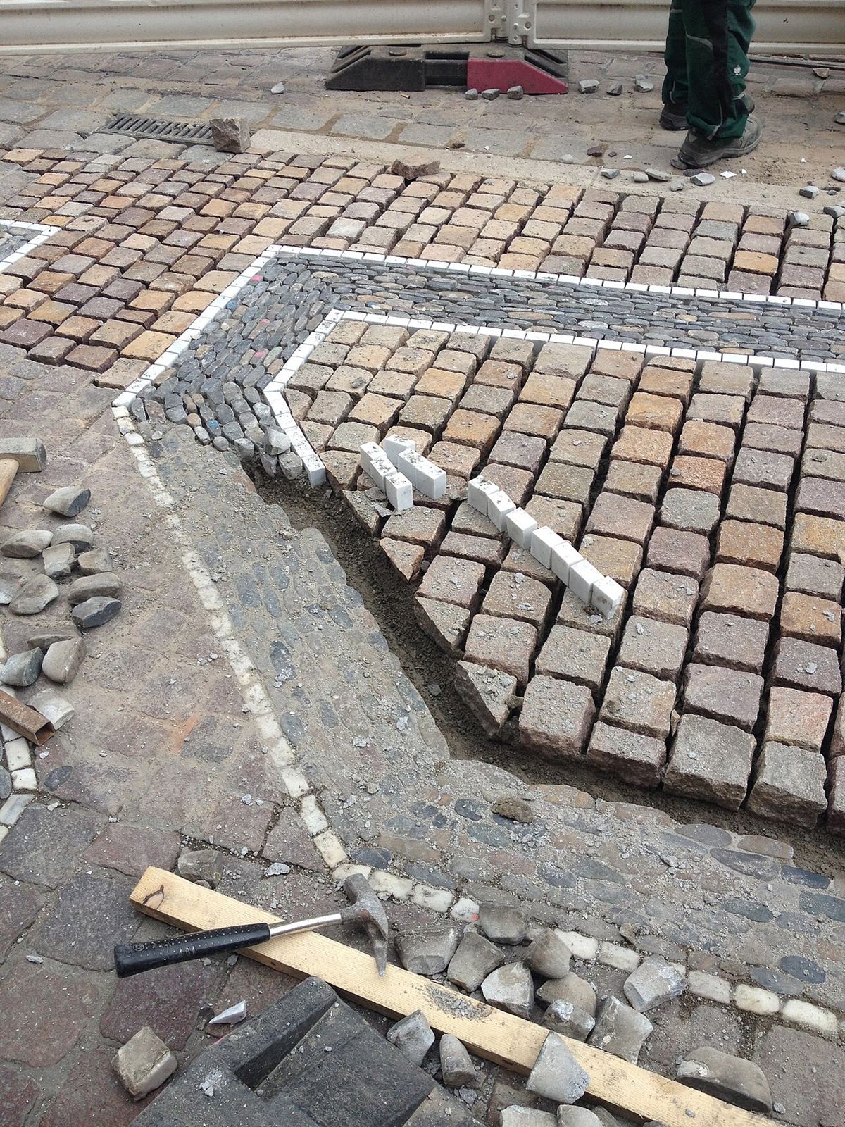 Sett paving stones being laid in a patterned surface